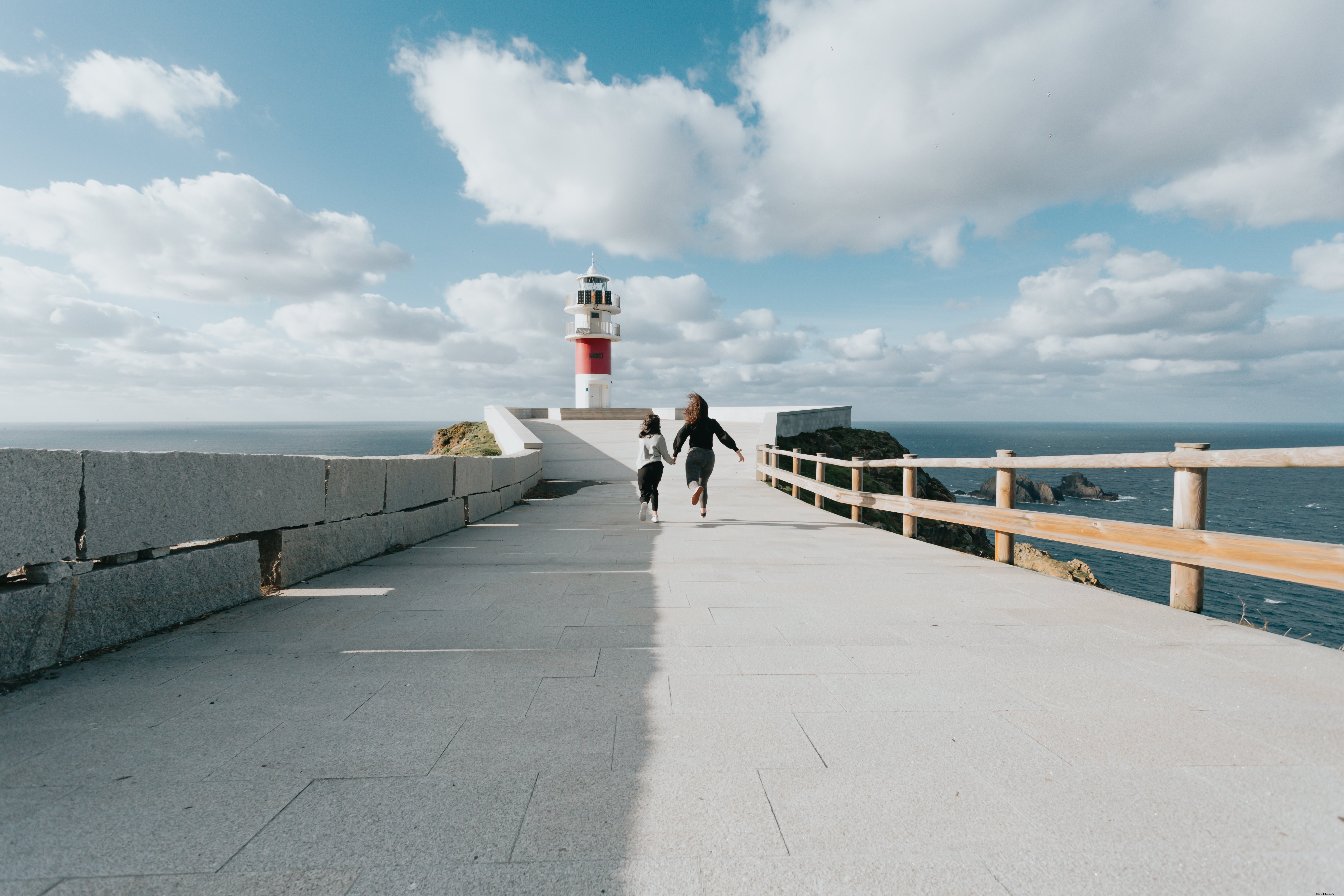 Stunning Photo: Two Runners Sprinting Down Paved Road to Majestic Lighthouse