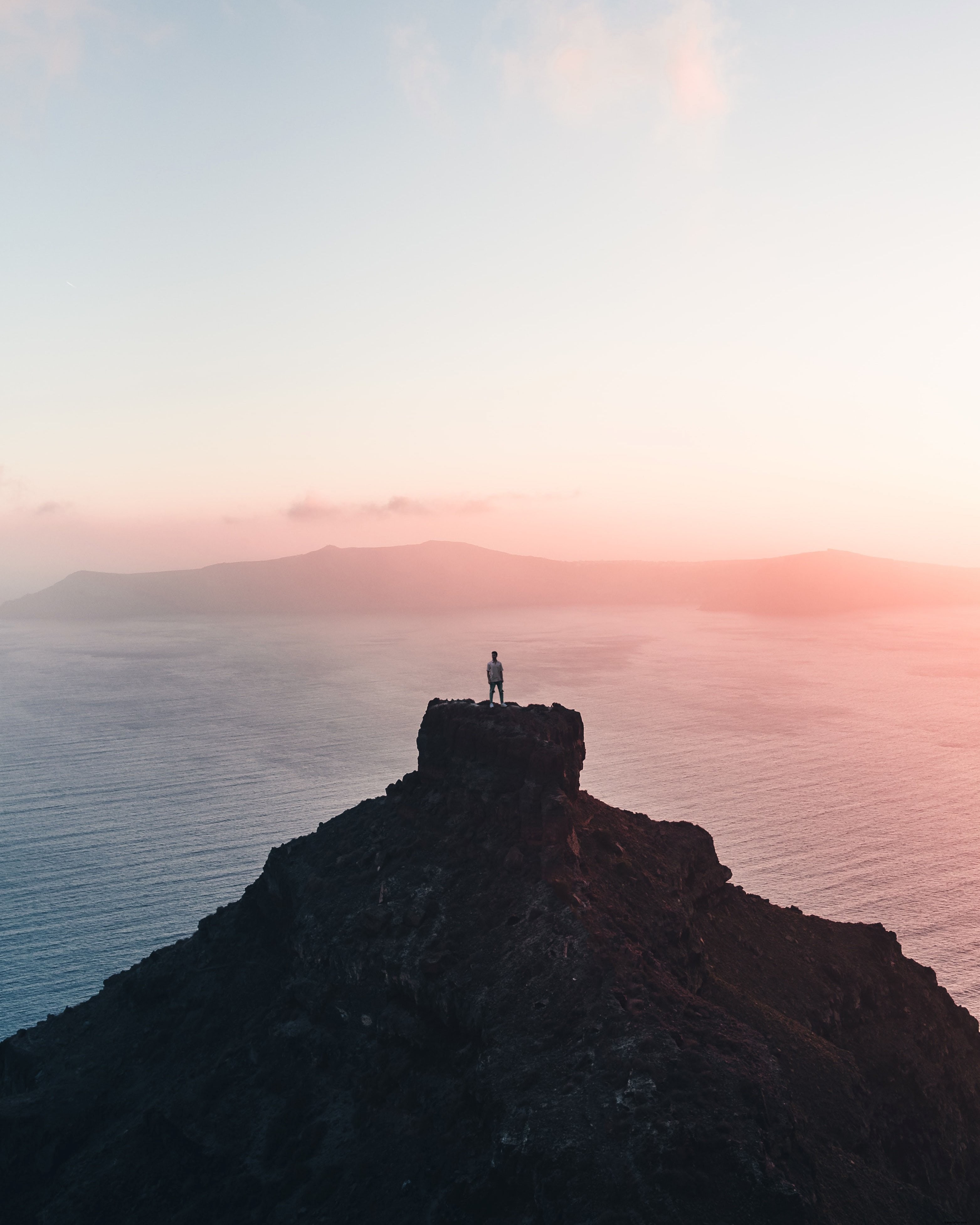 Lone Photographer on Distant Cliff Captures Stunning Sunset