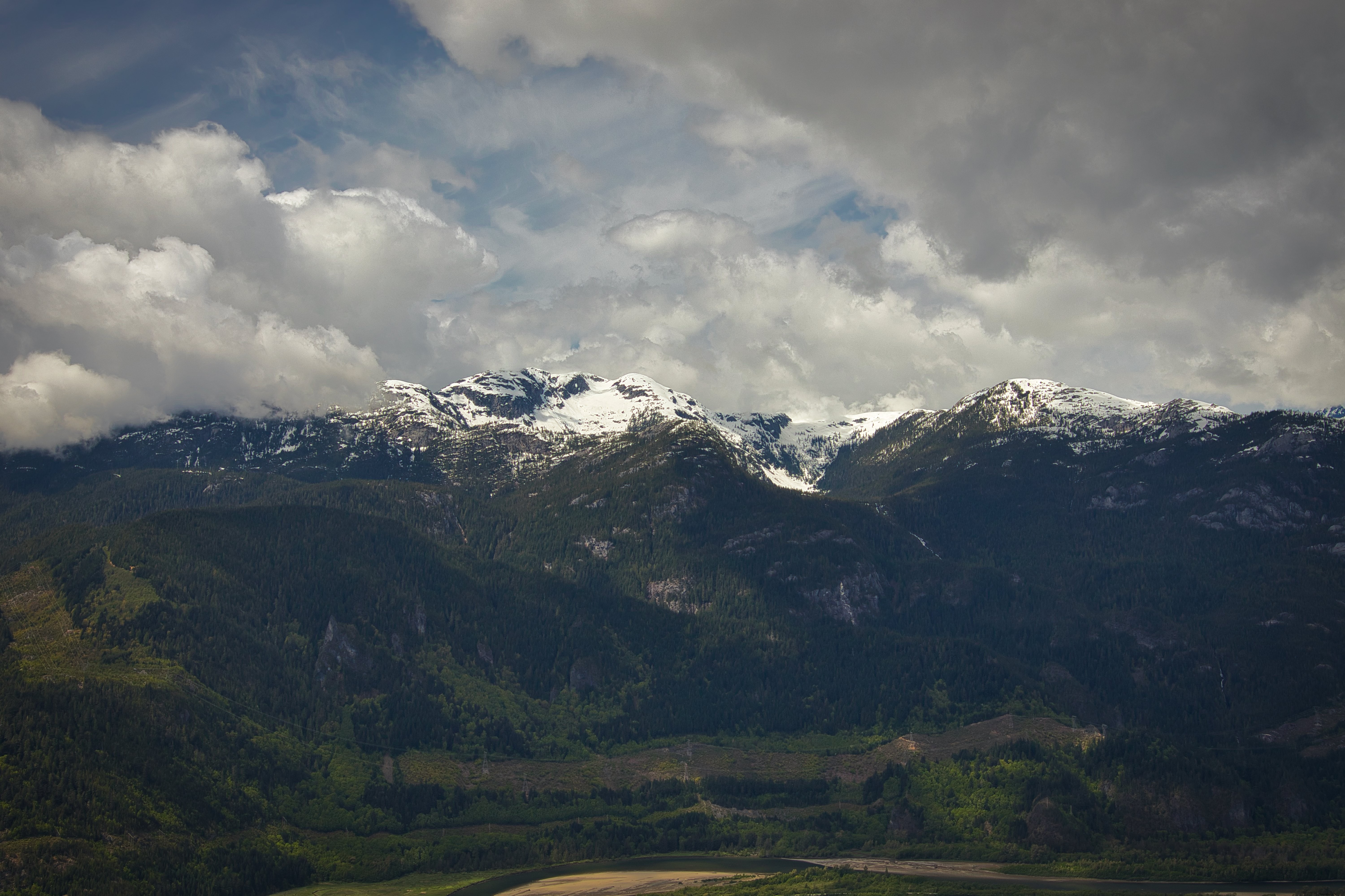 Majestic Snow-Capped Green Mountains Under Fluffy Clouds – Stunning Photo