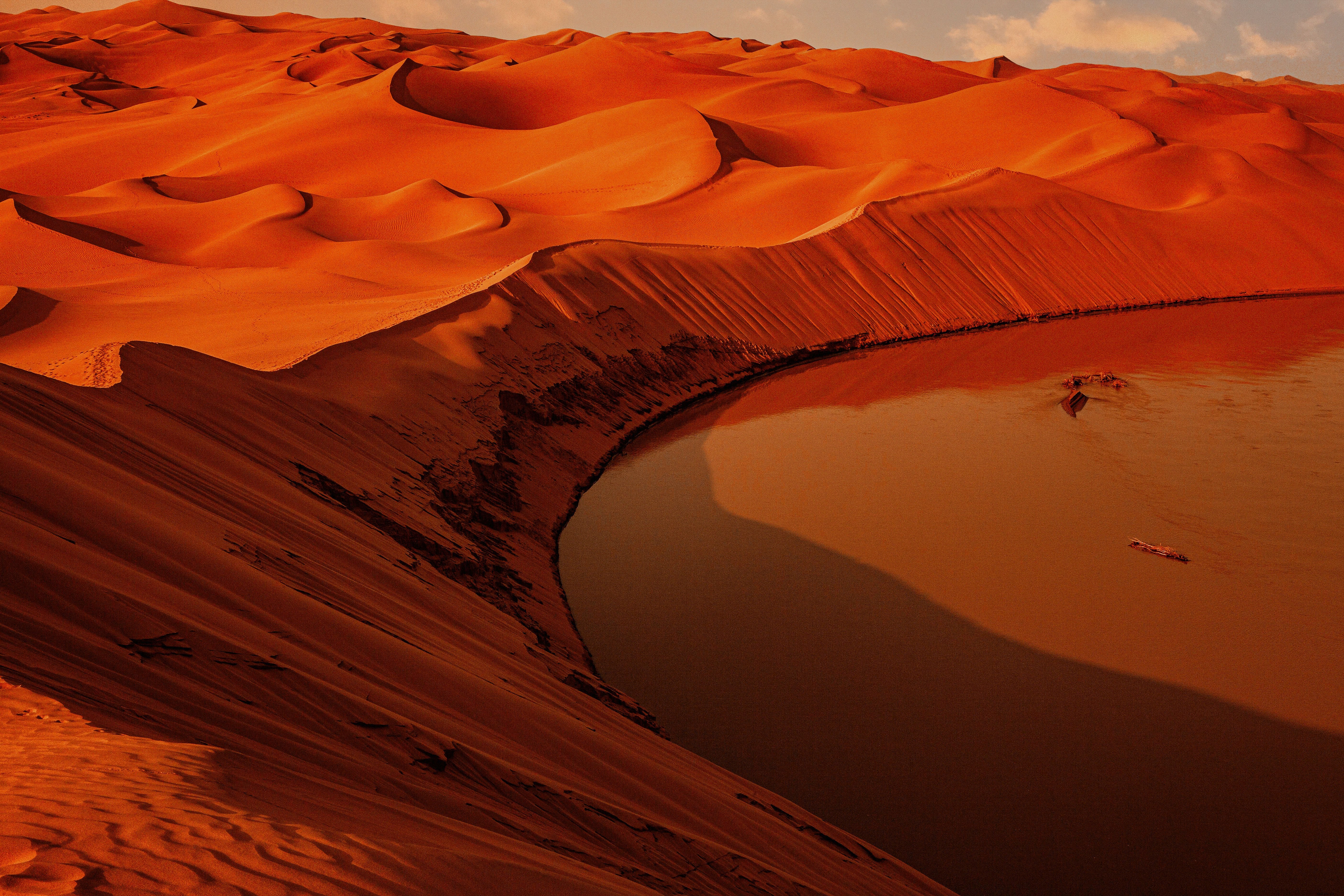 Stunning Landscape: Vibrant Sandy Hills Curve into Serene Orange Waters