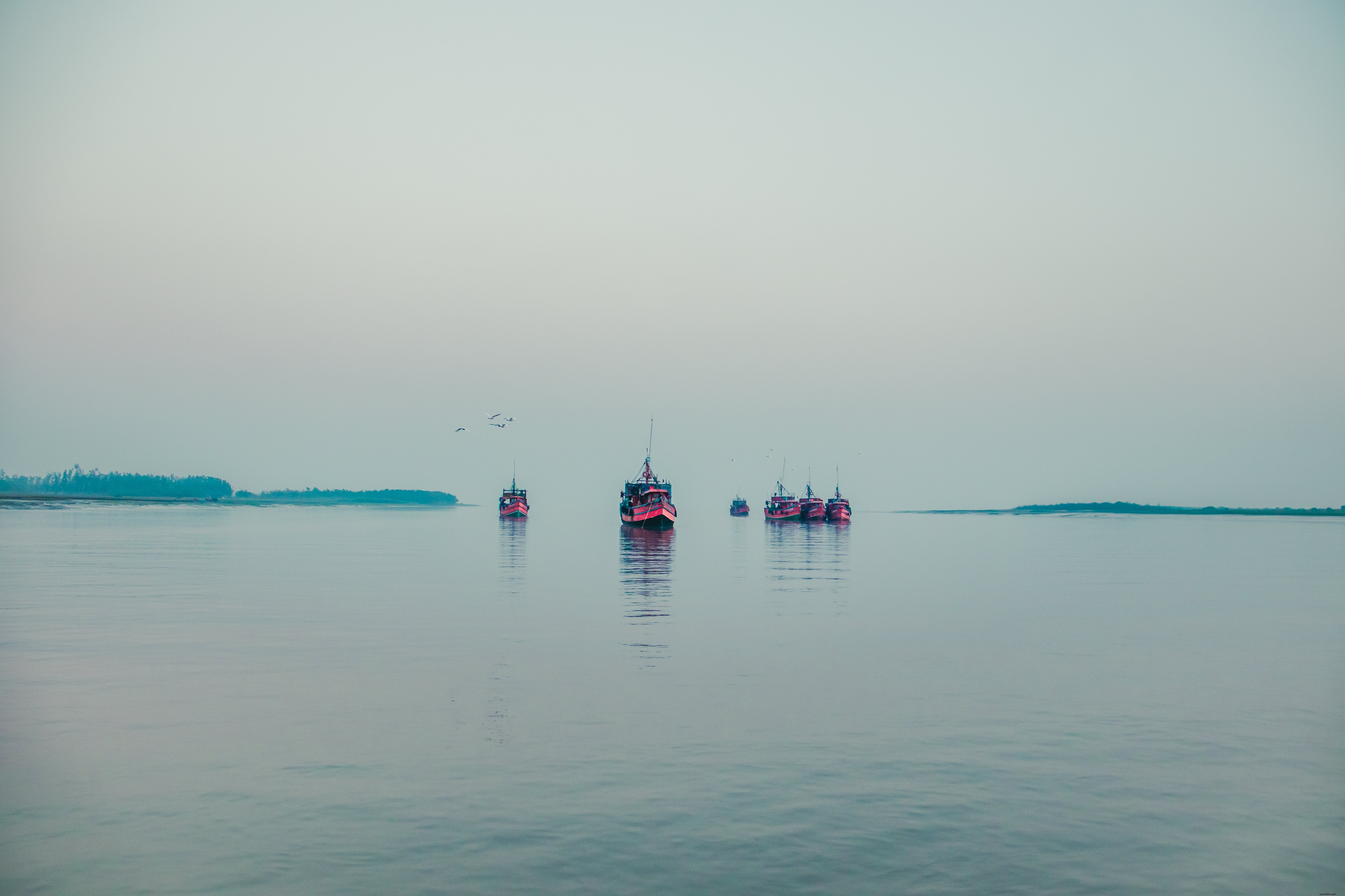 Serene Red Boats Drifting on Calm Waters Under Overcast Skies – Stunning Photo