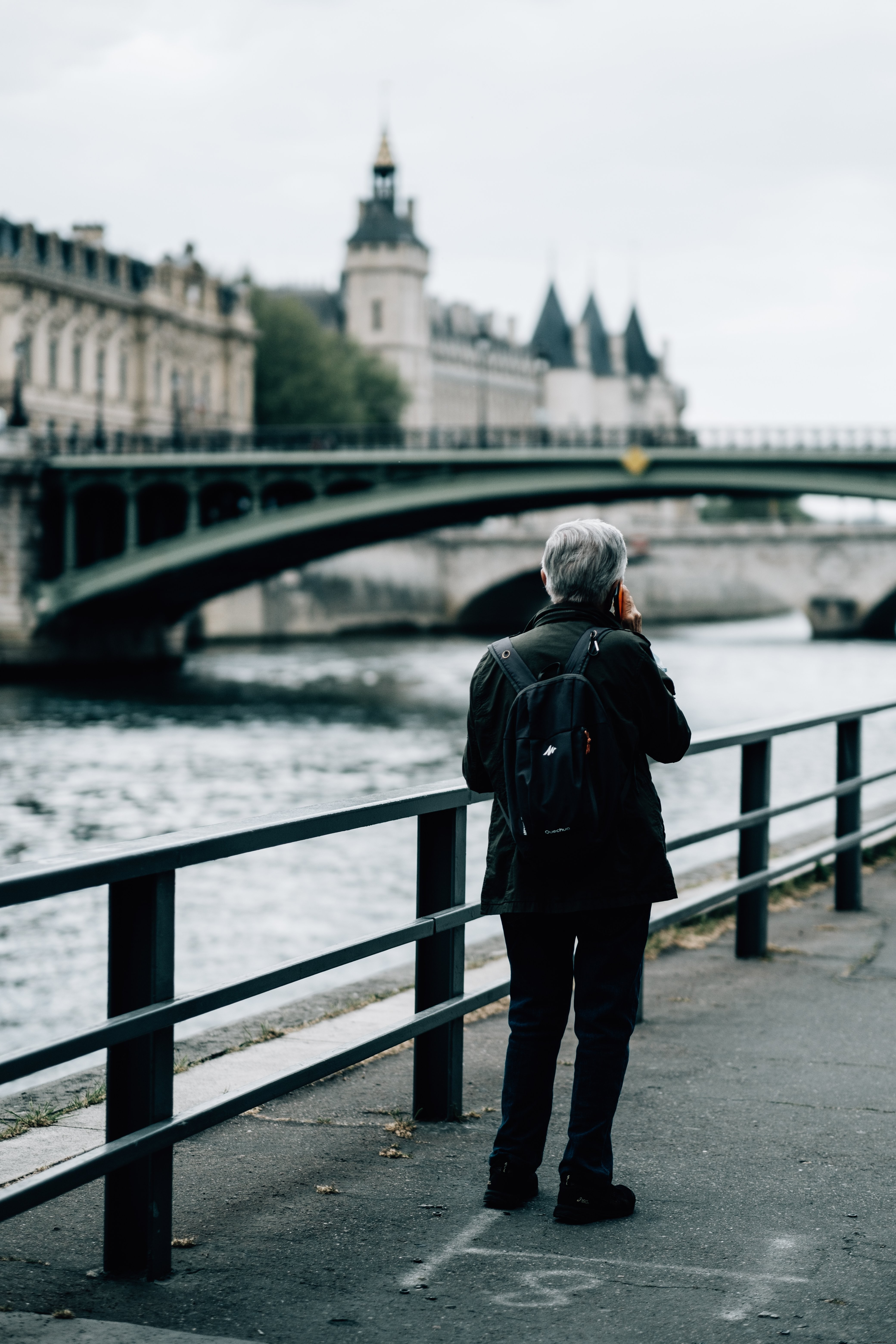Photo: Person Stands by River, Chatting on Phone