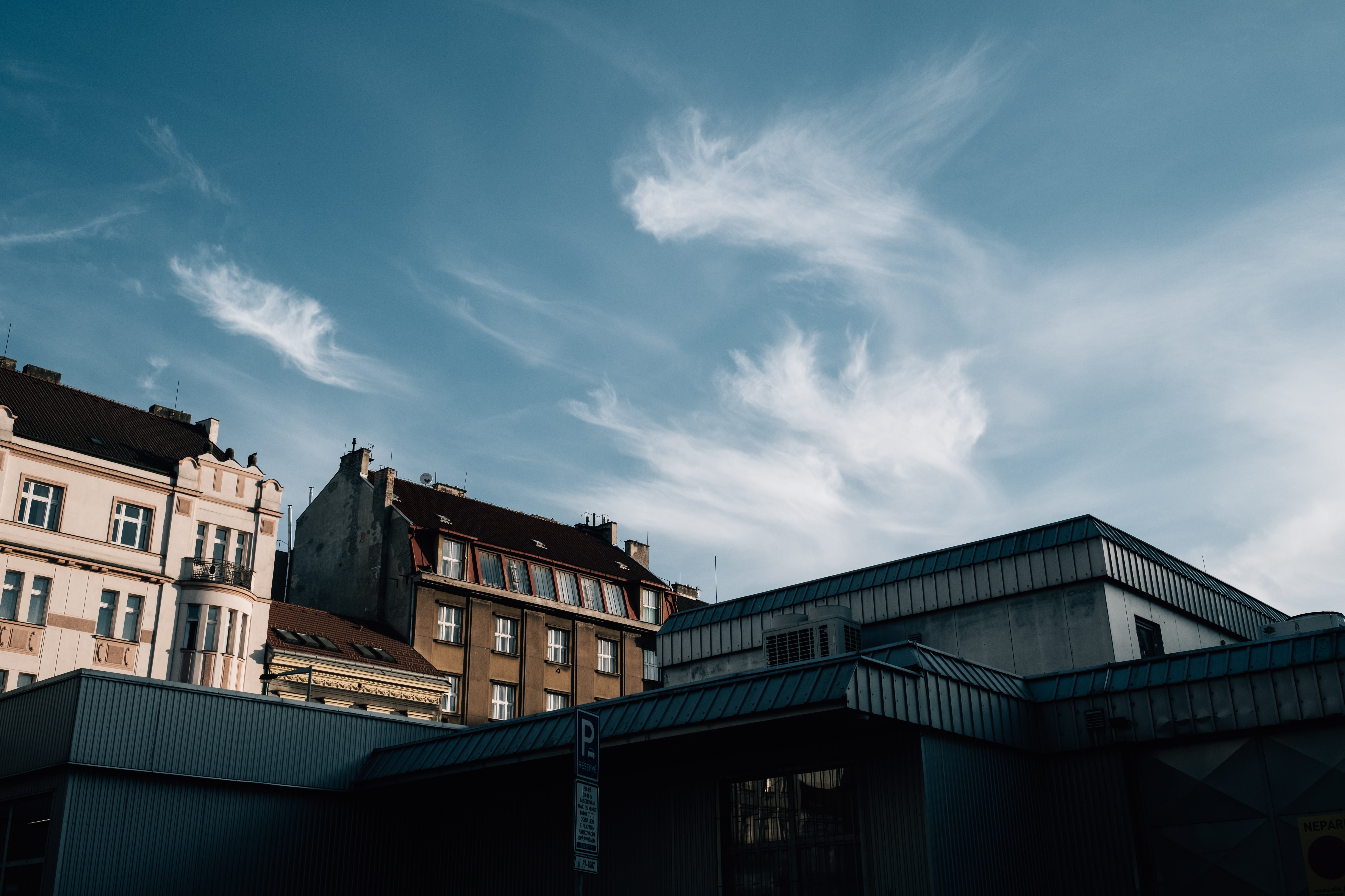 Vivid Skyline: Blue Skies and Wispy Clouds Above Urban Rooftops