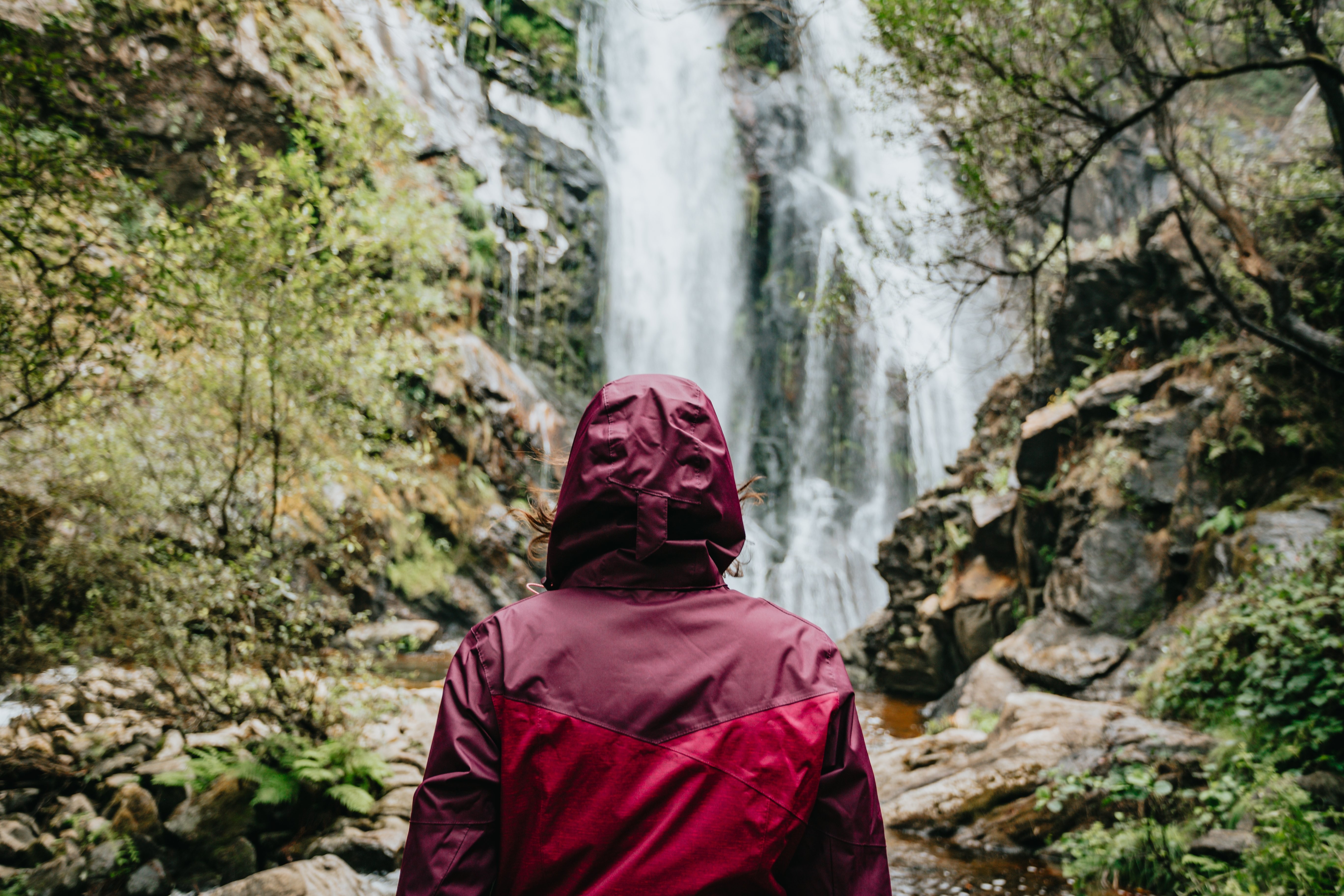 Exploring a Majestic Waterfall: A Raincoat-Wearing Visitor s Stunning Perspective