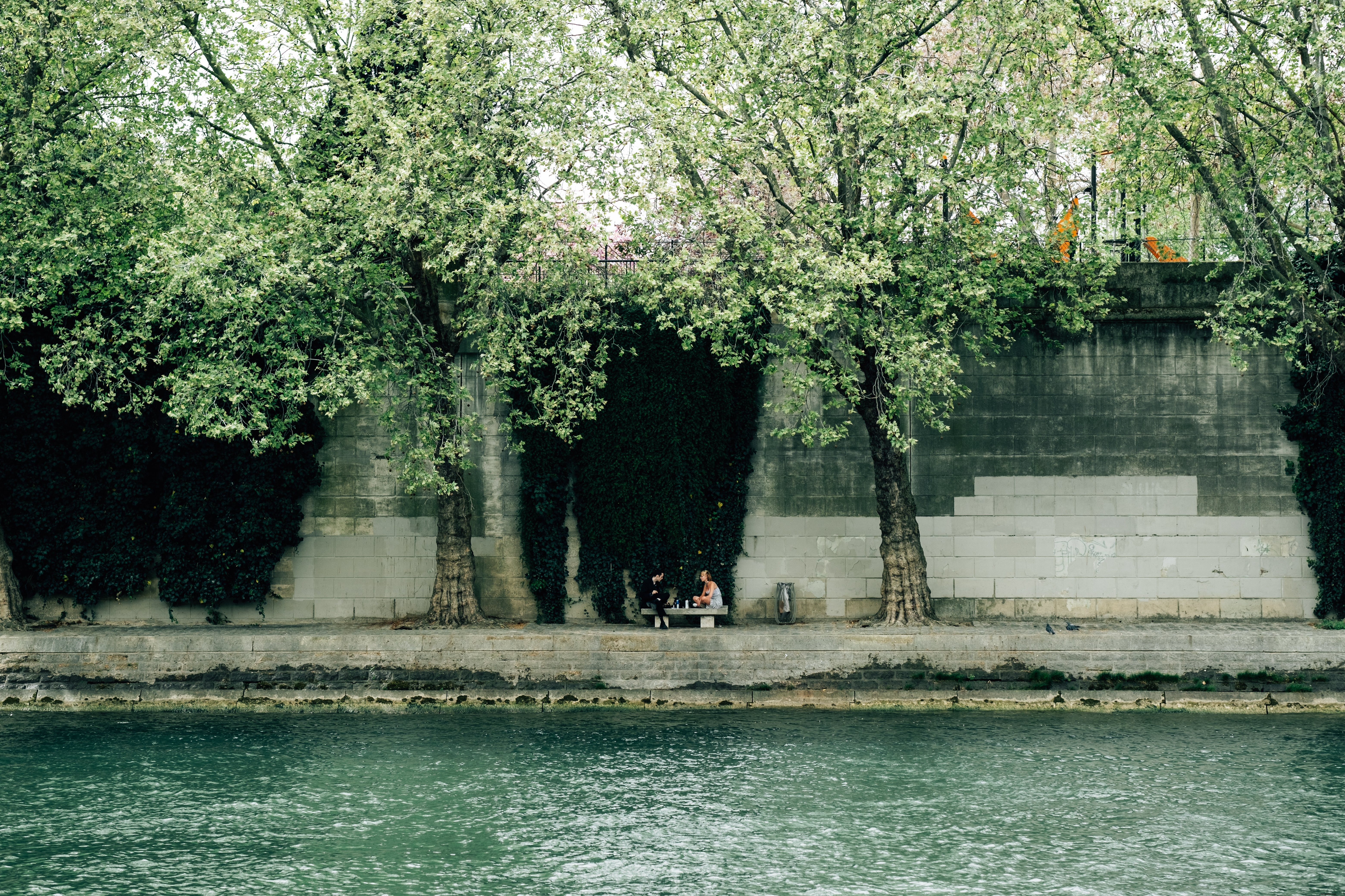 Serene Riverside Scene: Viewers Relax on a Bench Across the Water