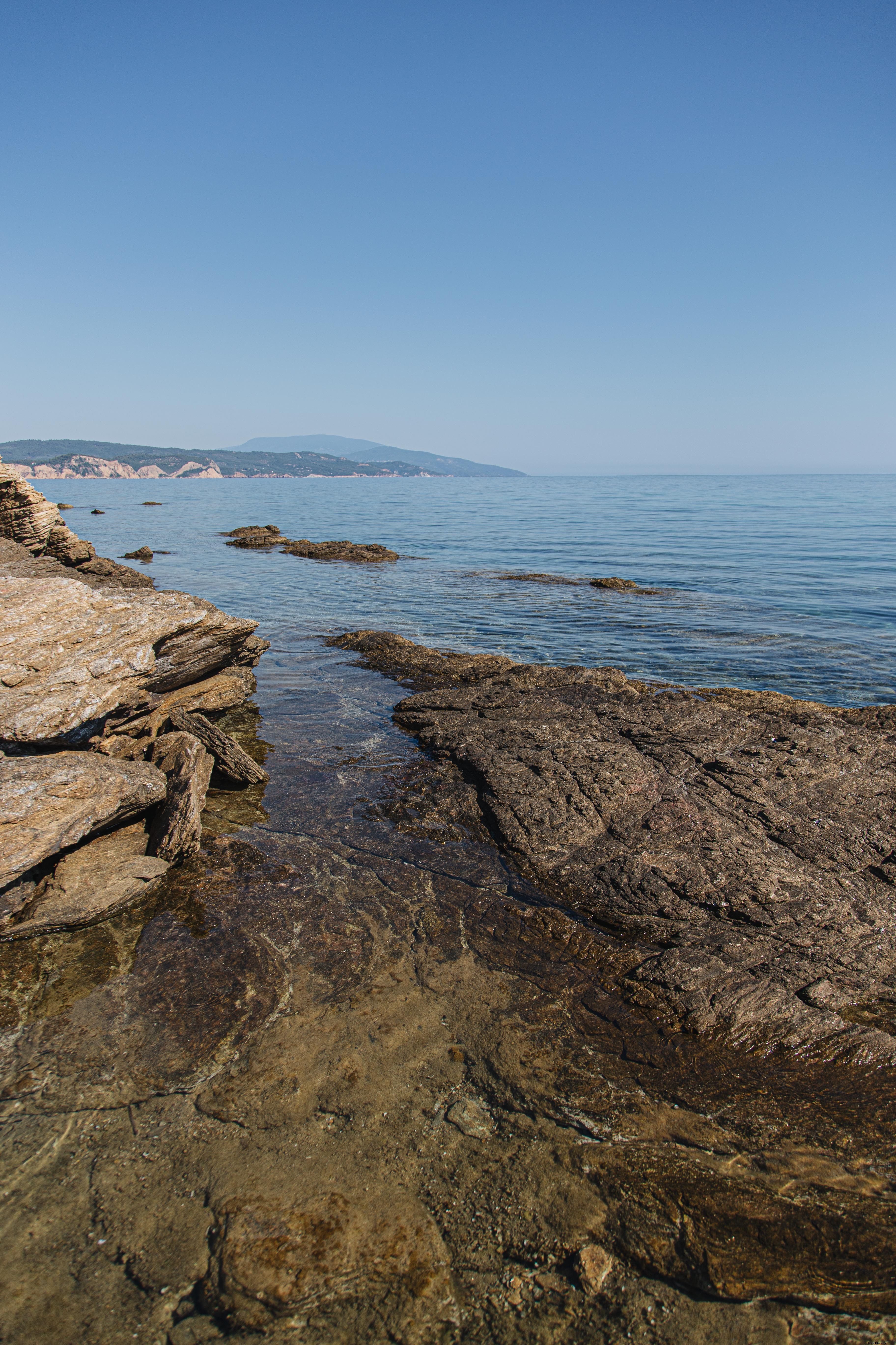 High‑Resolution Rocky Coast Overlooking the Open Ocean Under a Clear Blue Sky