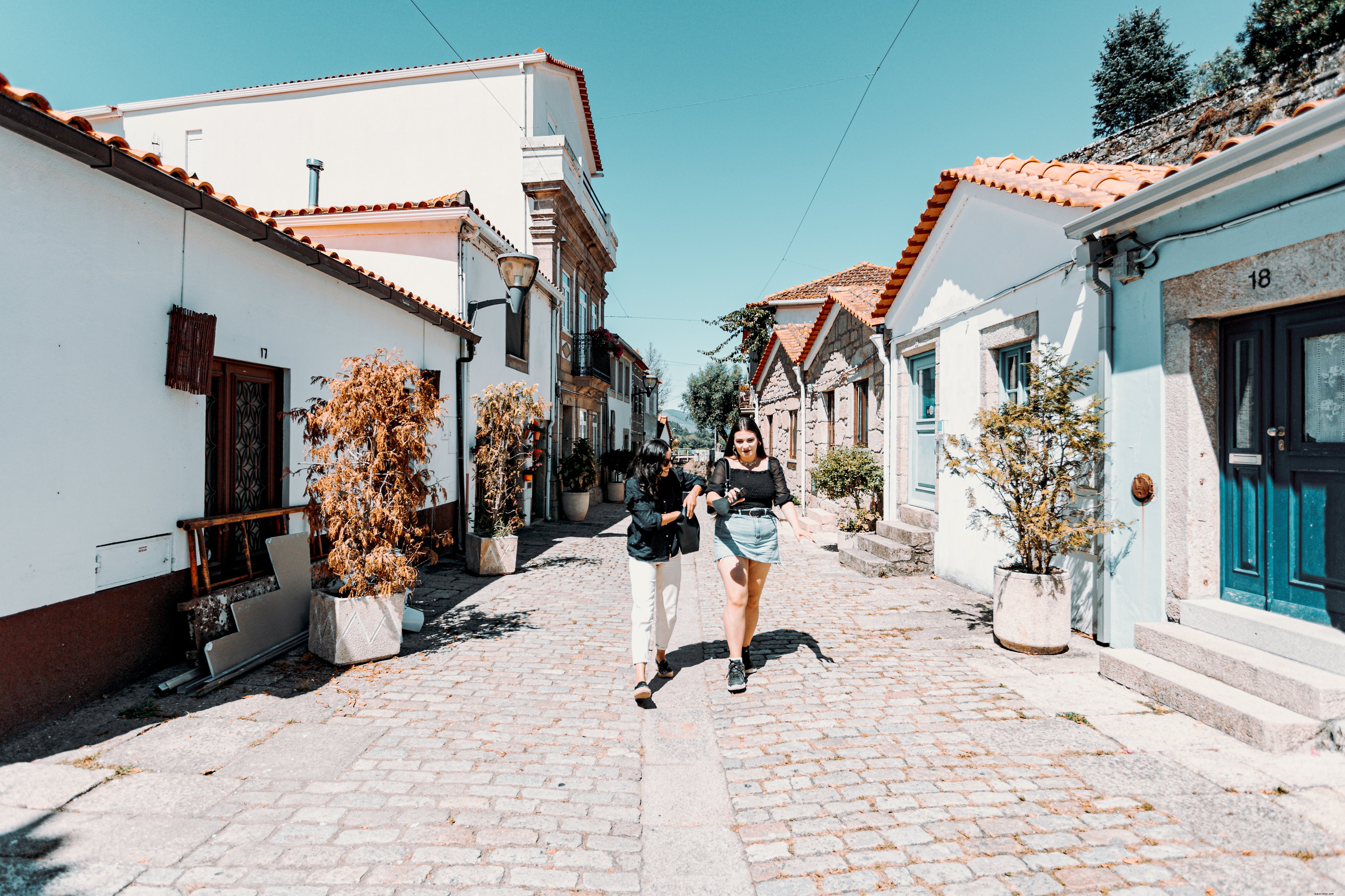Two Women Stroll Side by Side Along a Building-Lined Pathway