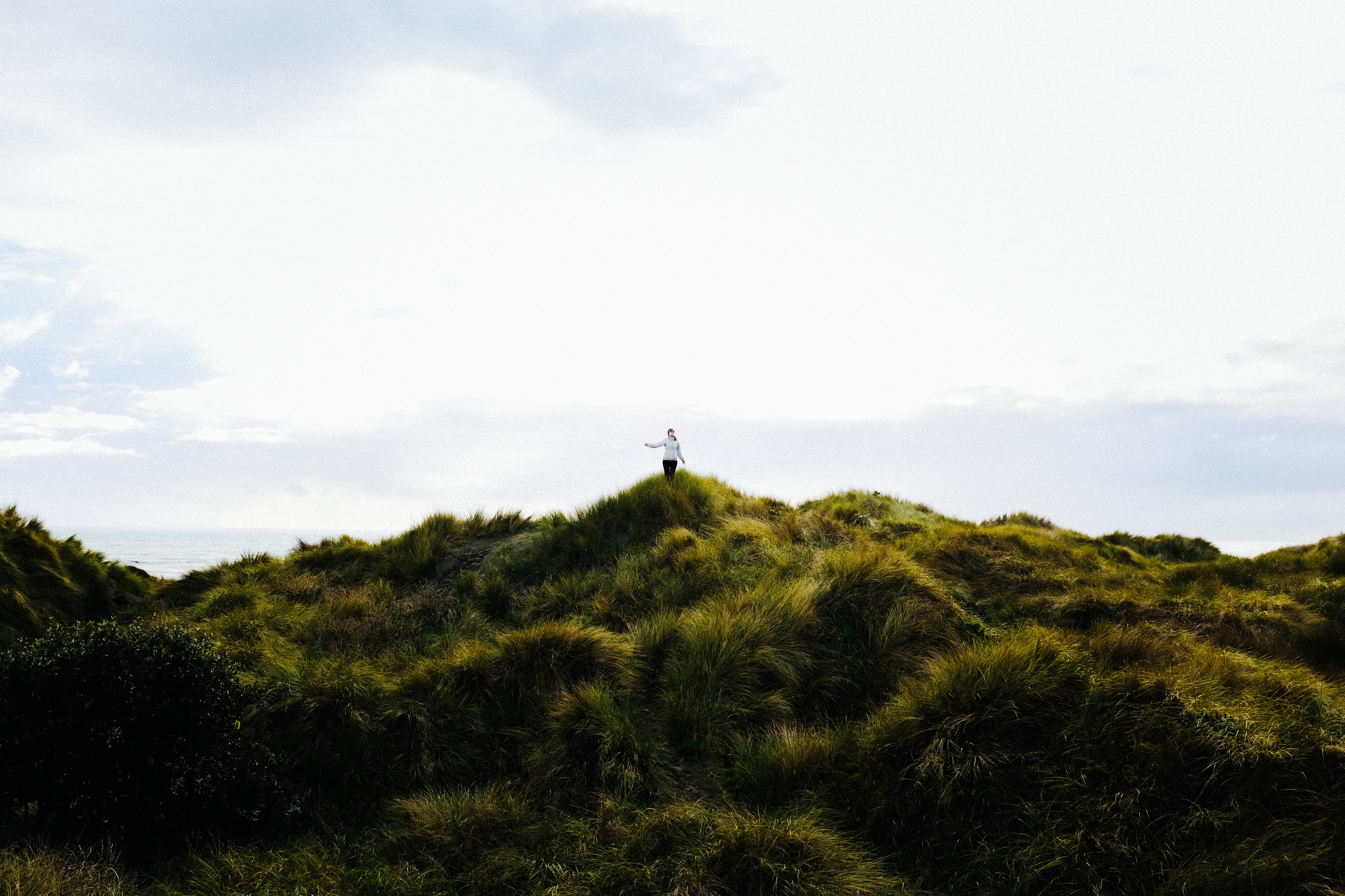 Stunning Landscape Photo: Woman Walks Across Expansive Green Dunes