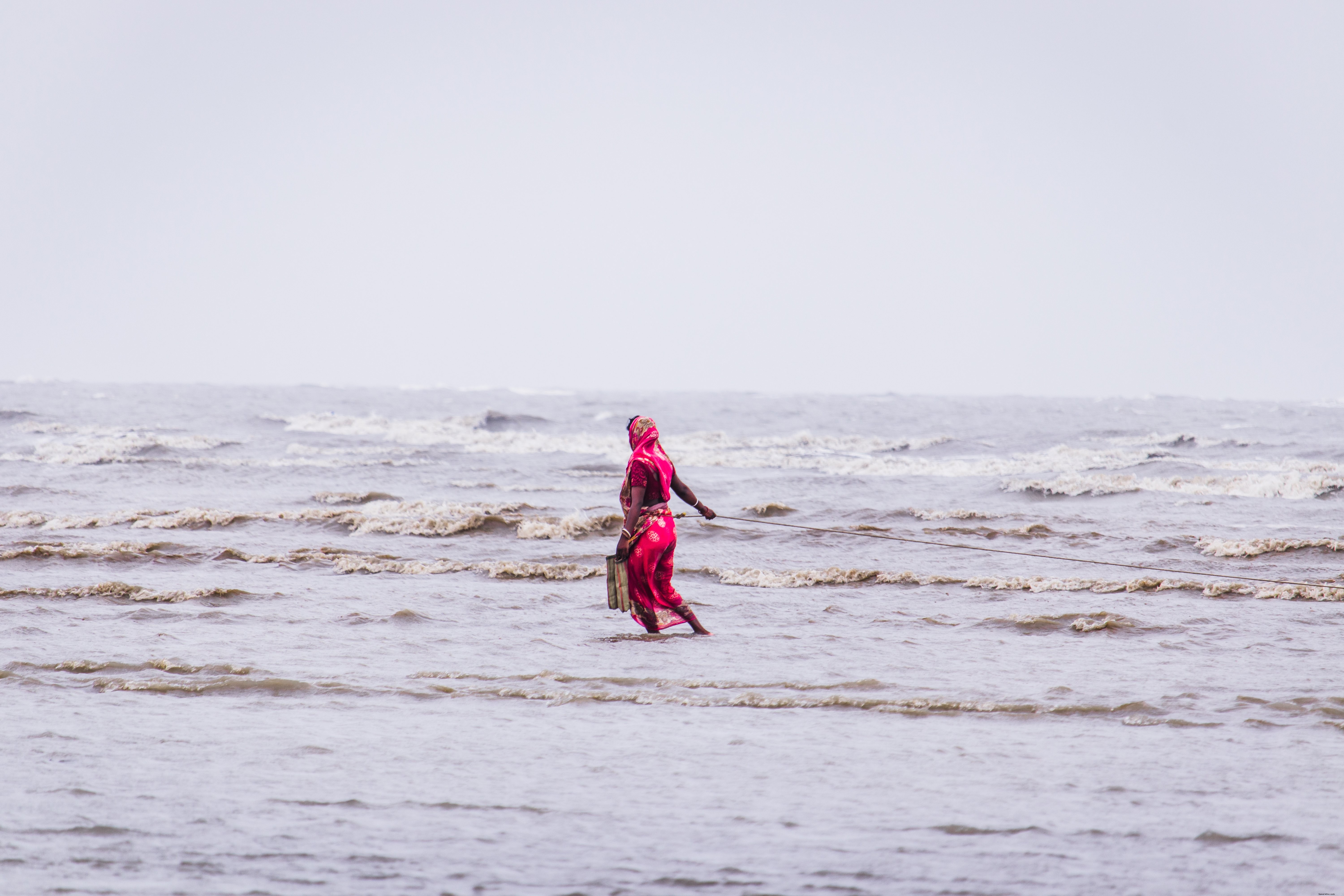 Woman in Red Strolls Through Shallow Waters – A Captivating Photo