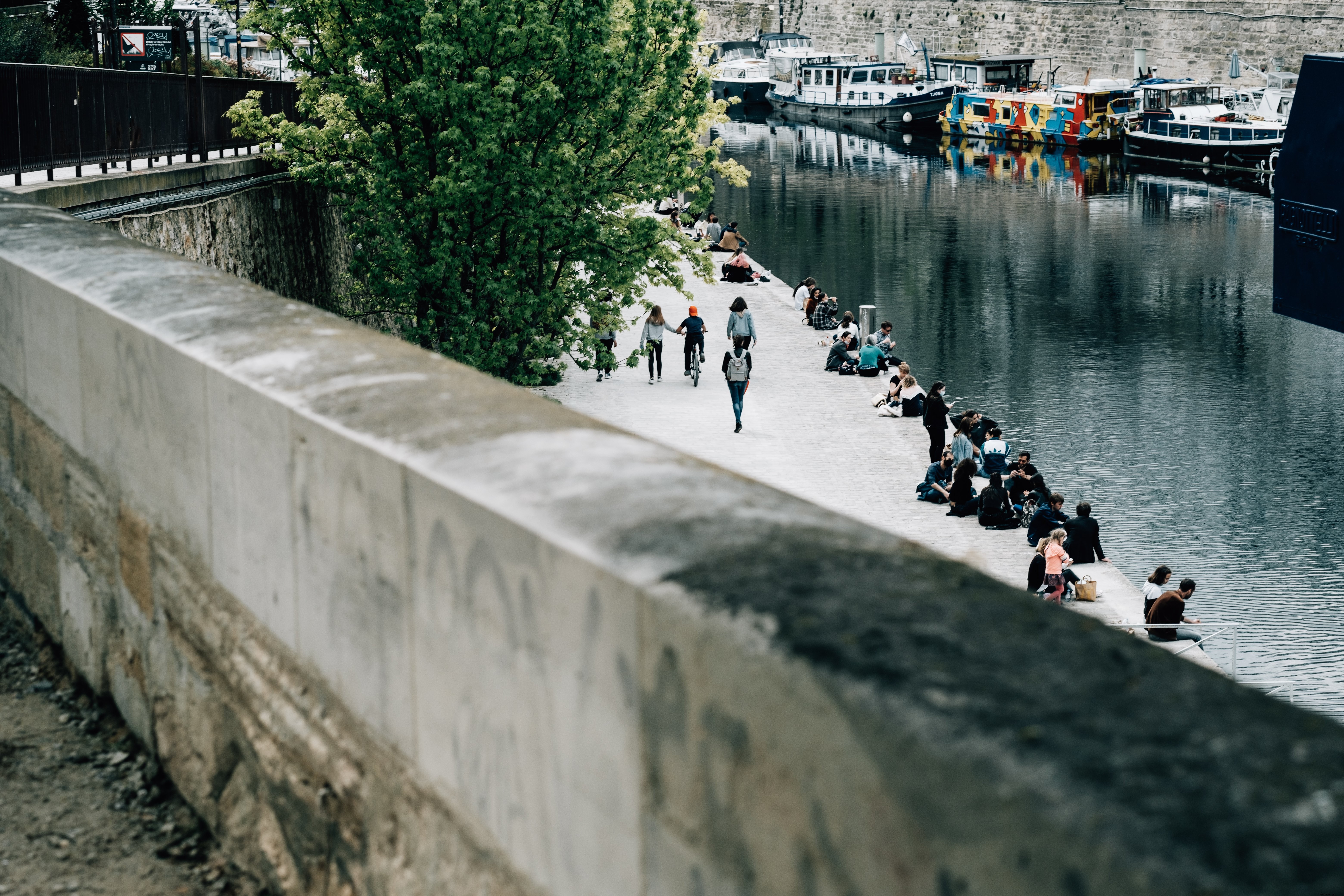 Calm Canal Scene: People Relaxing While Boats Drift Along the Shore