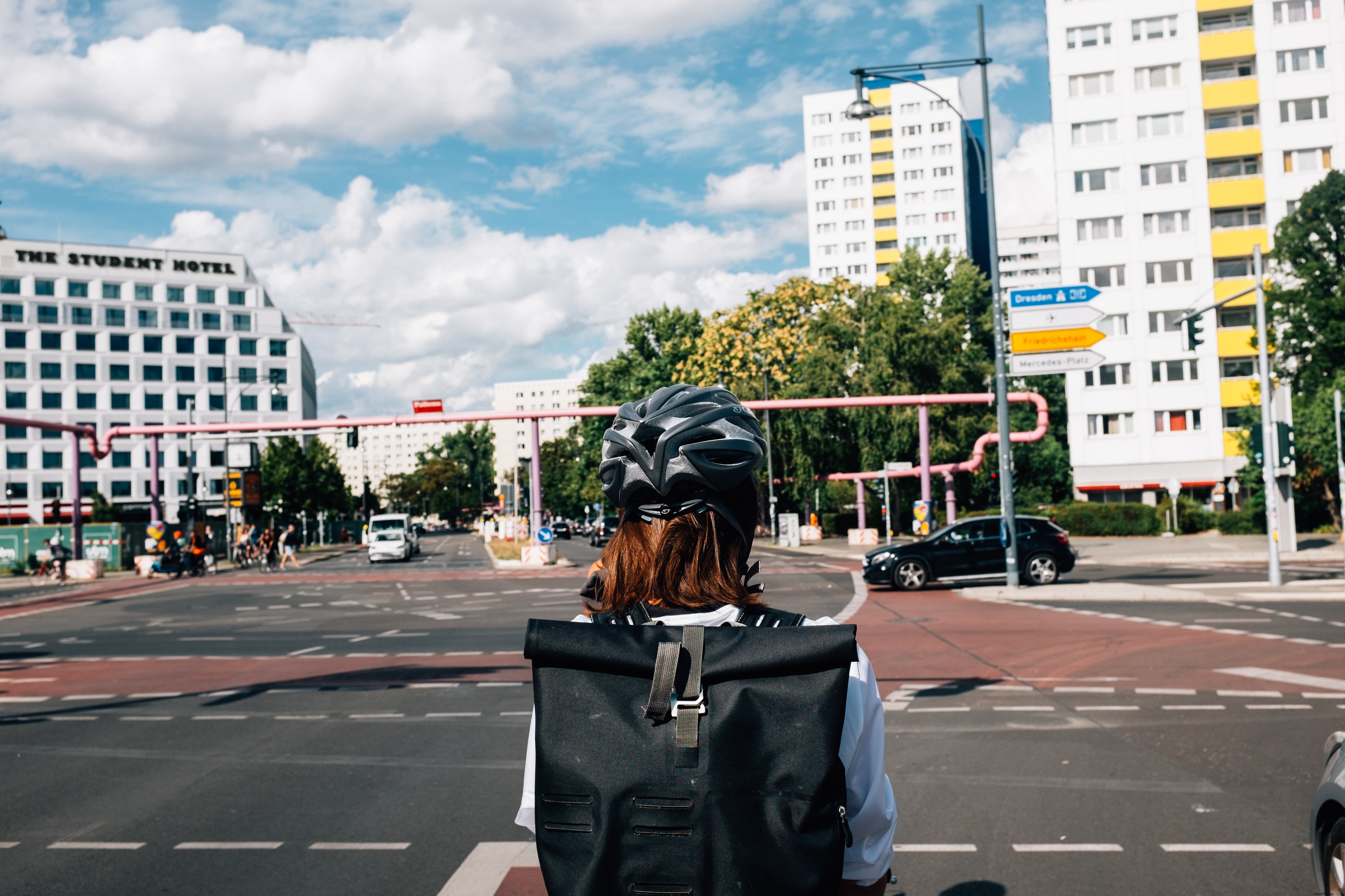 Helmeted Pedestrian Waits at a Busy City Intersection
