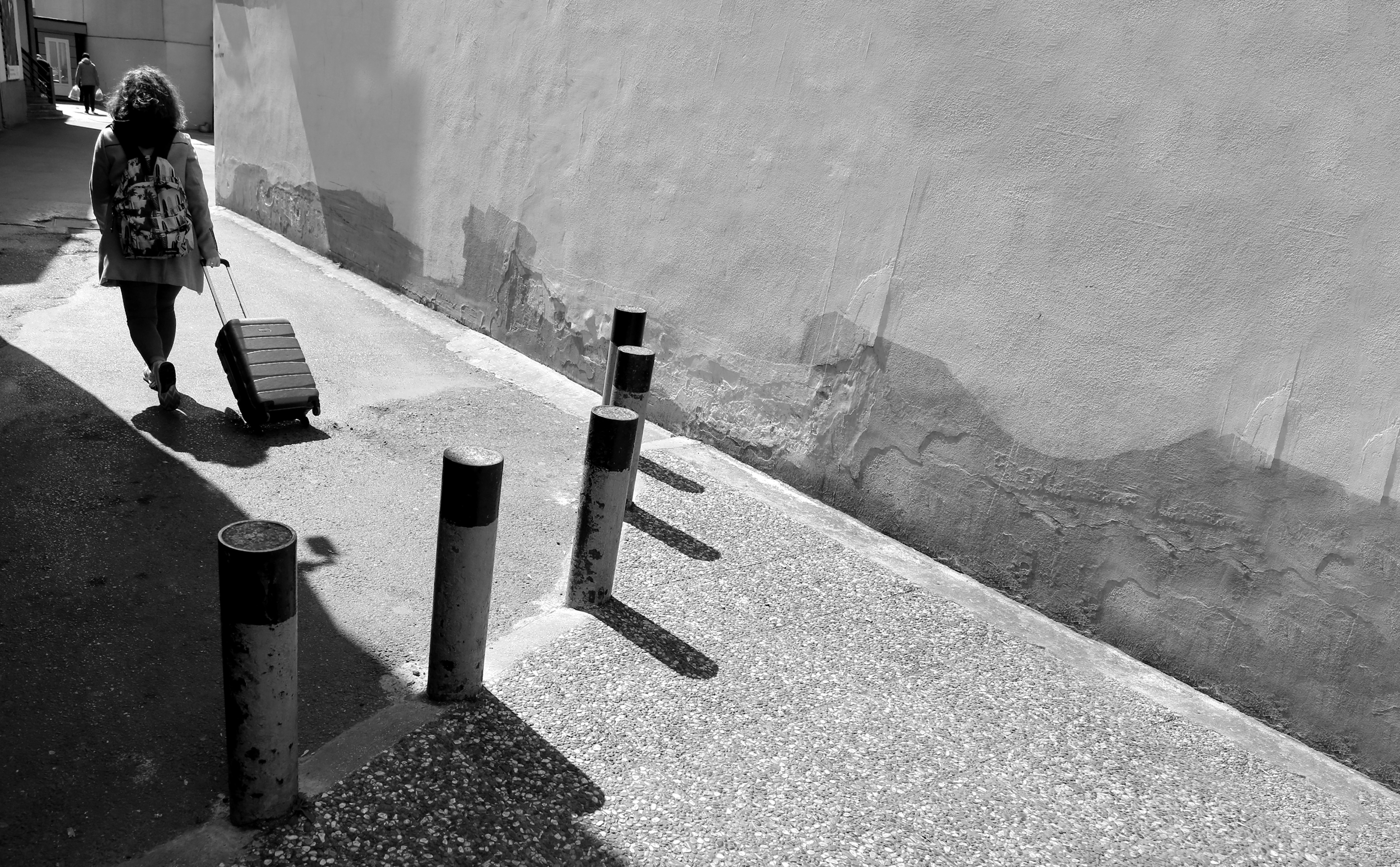 Stroll Through a Charming Side Street: A Traveler with Luggage Captured in Action