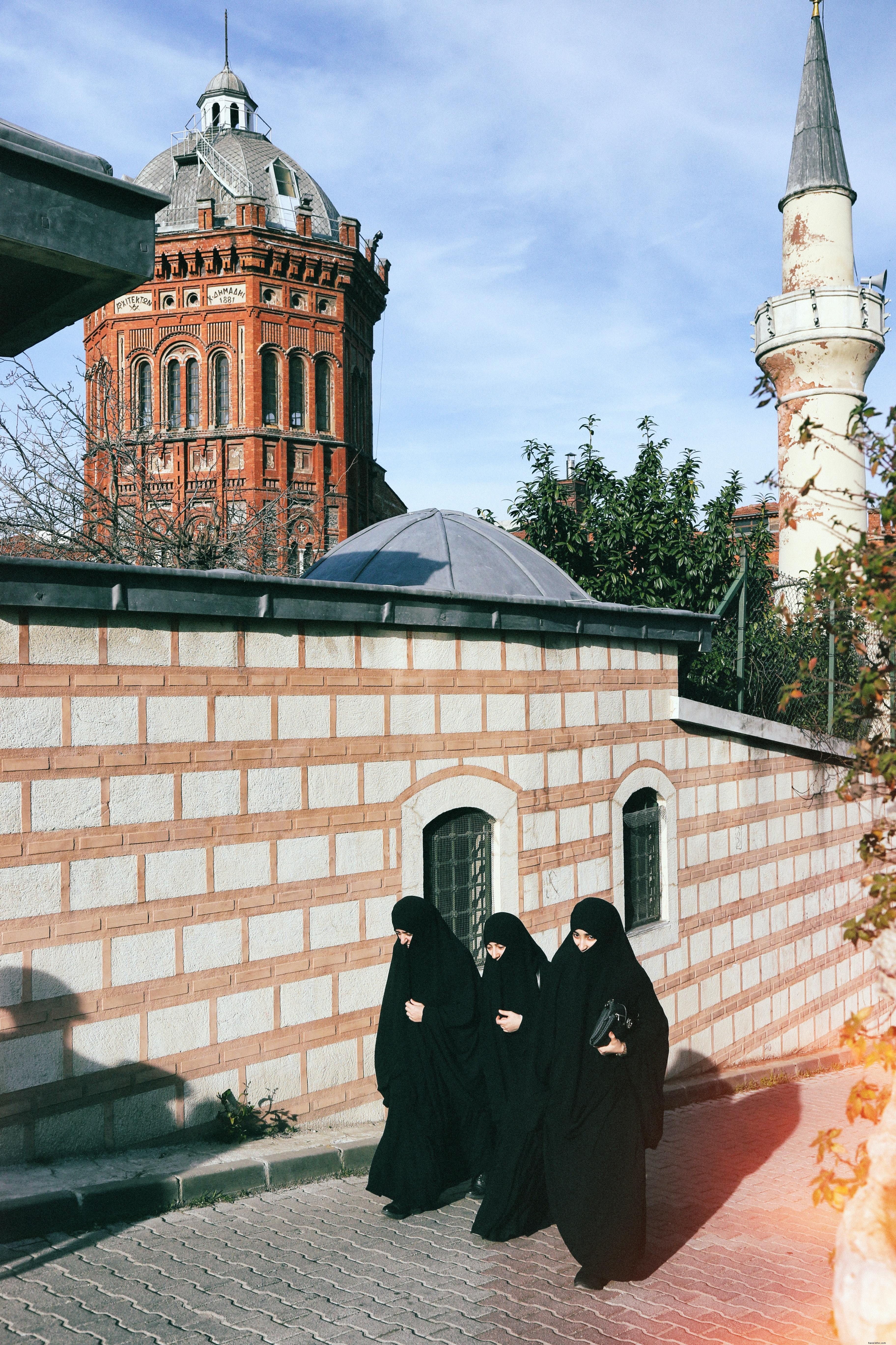 Three Individuals in All-Black Attire Walk Together Through a City Street – Group Photo