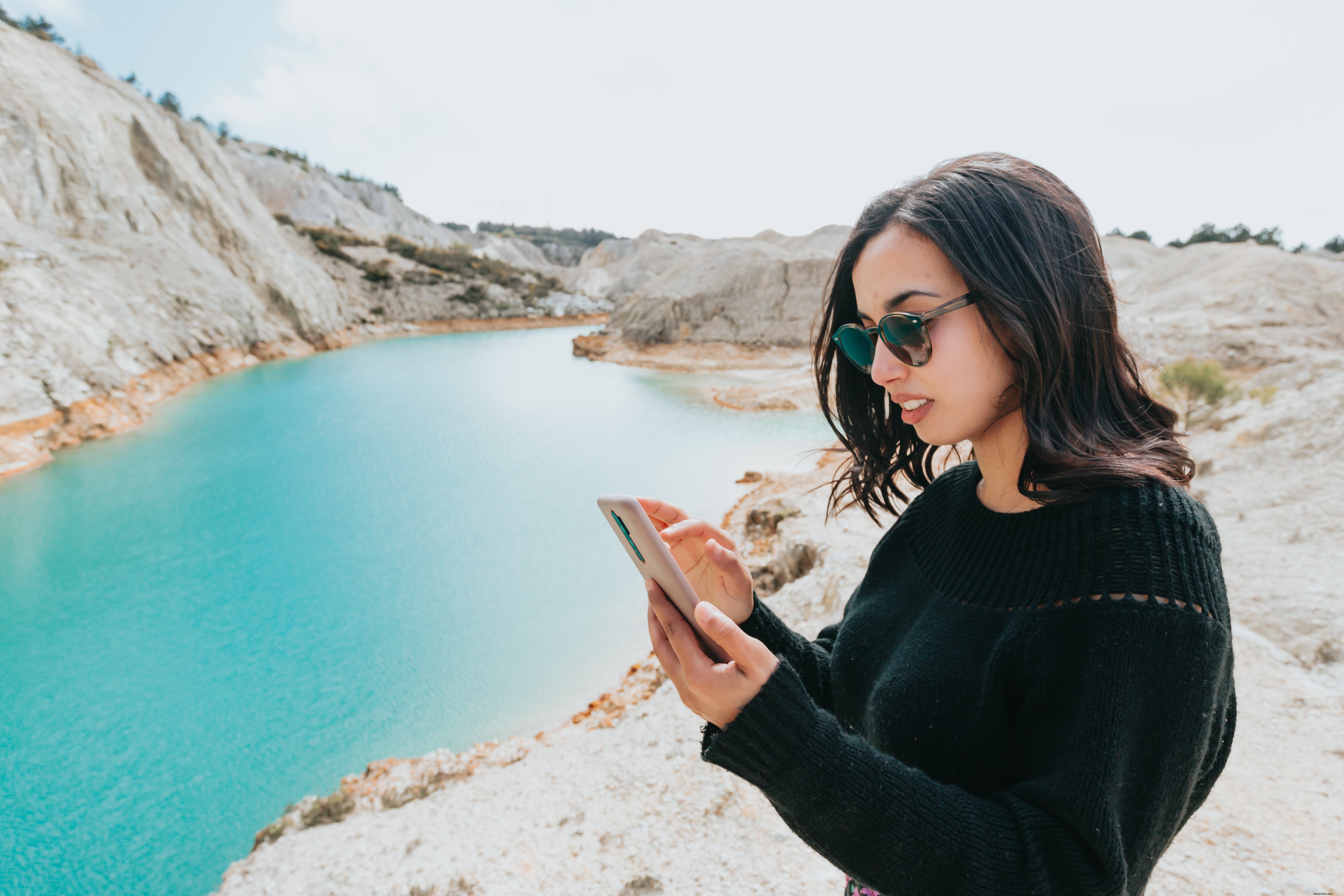 Serene Moment: Woman Uses Phone by Tranquil Blue Waters