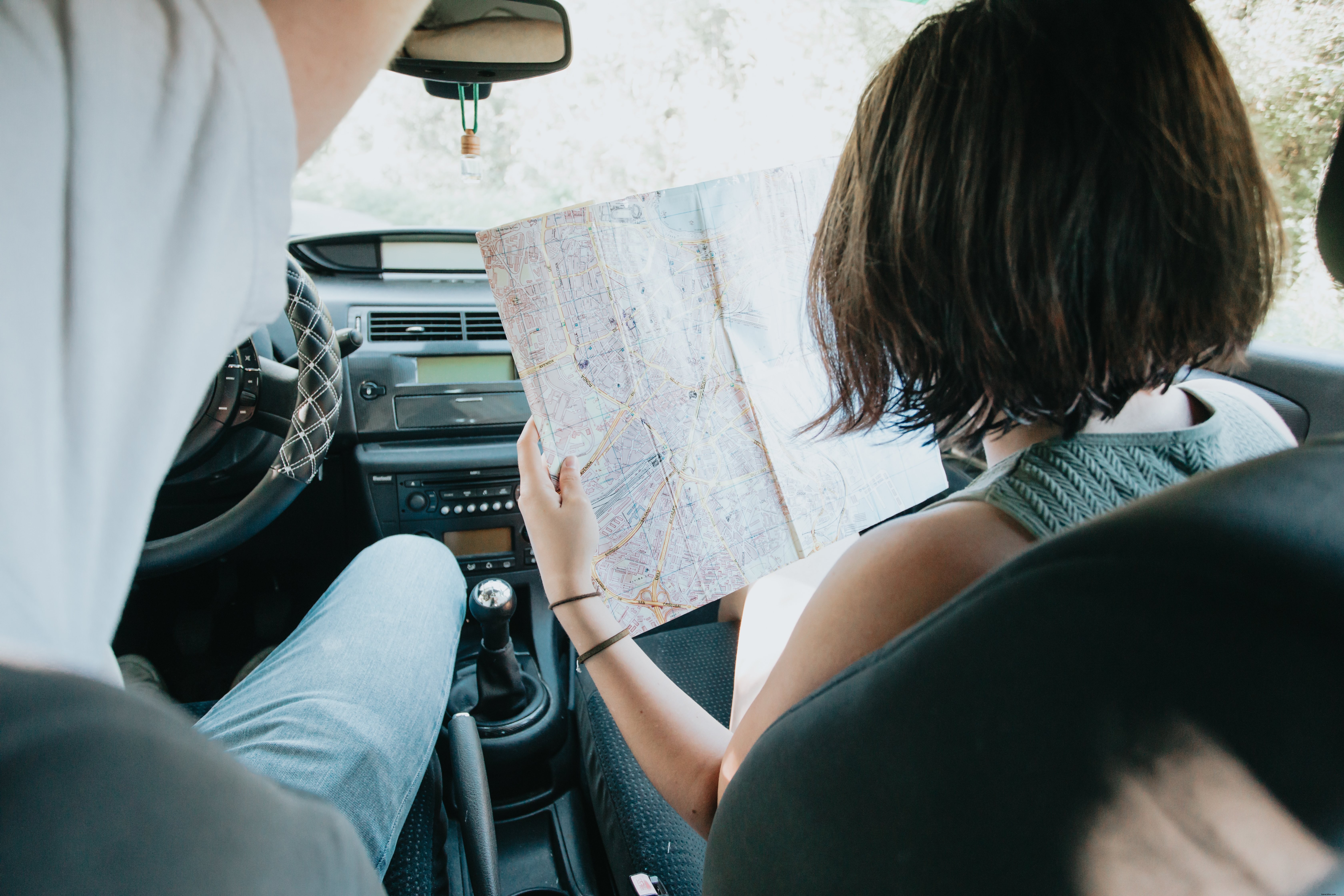 Photo: Two Travelers Holding a Large Map Inside a Car
