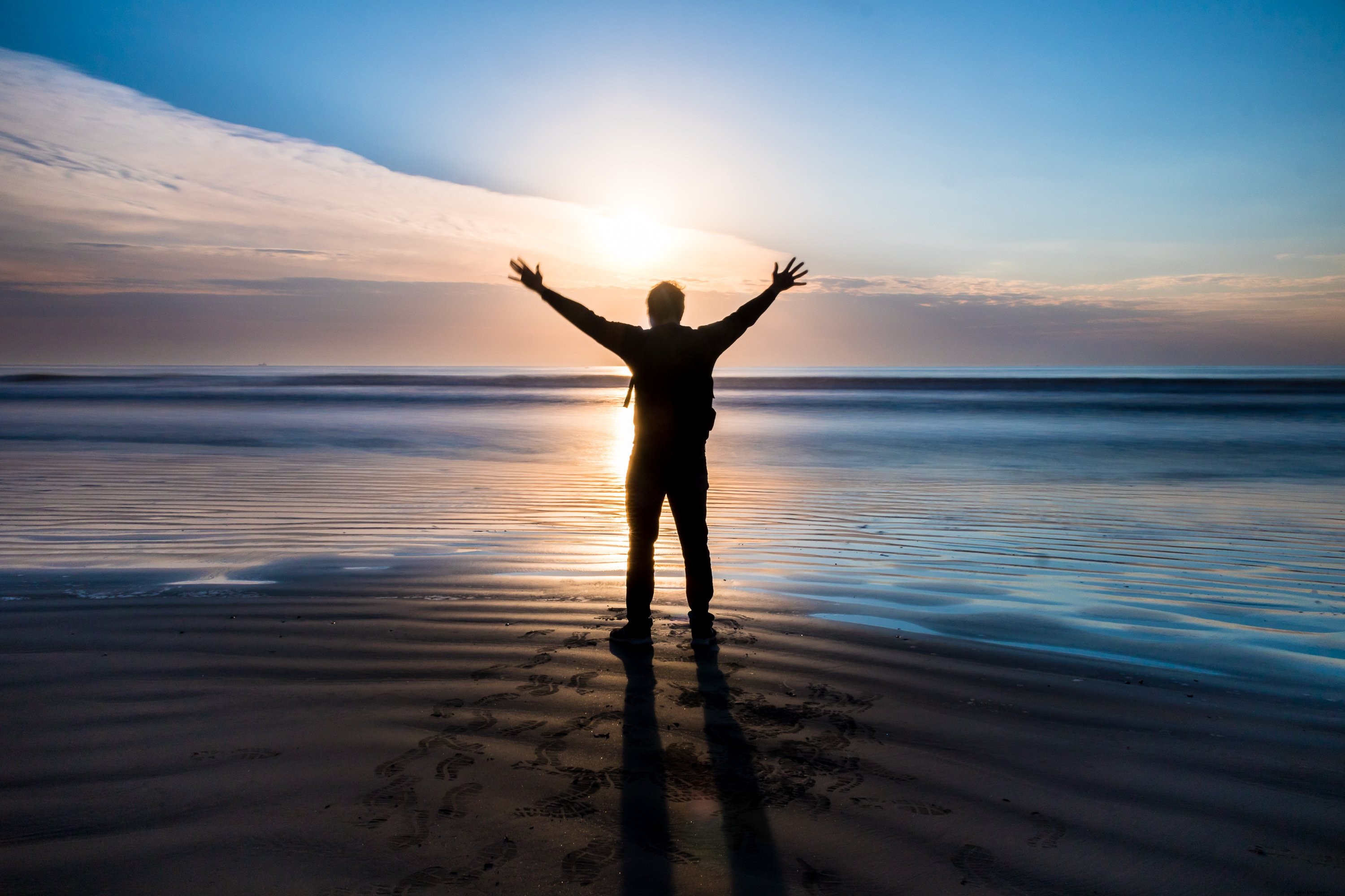 Sunset Beach Silhouette: Person Extending Arms at Dusk