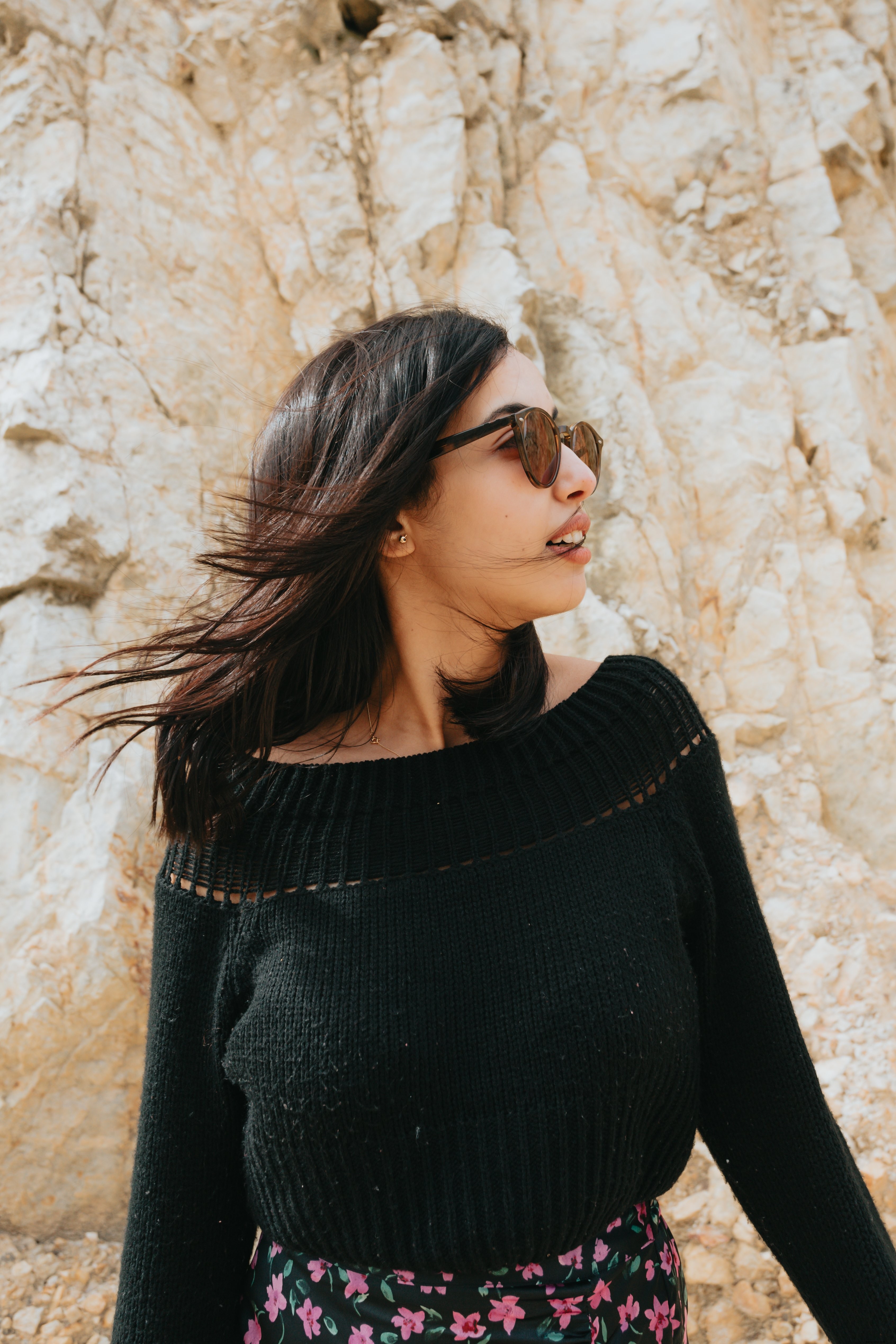 Stunning Portrait: Woman in Sunglasses Stands Before Rocky Landscape