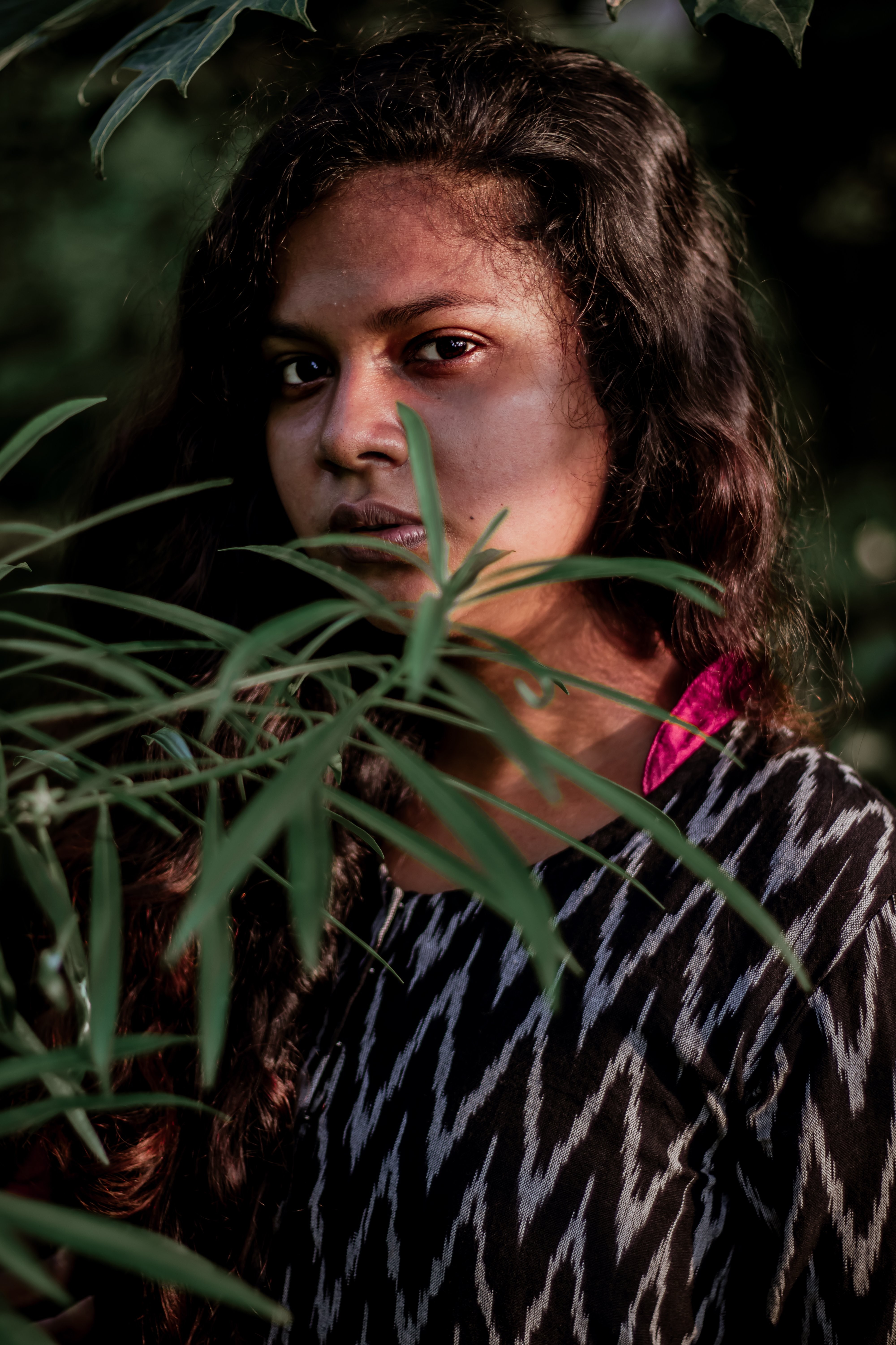 Intimate Portrait: Subject Looks Into the Camera Framed by Lush Green Leaves