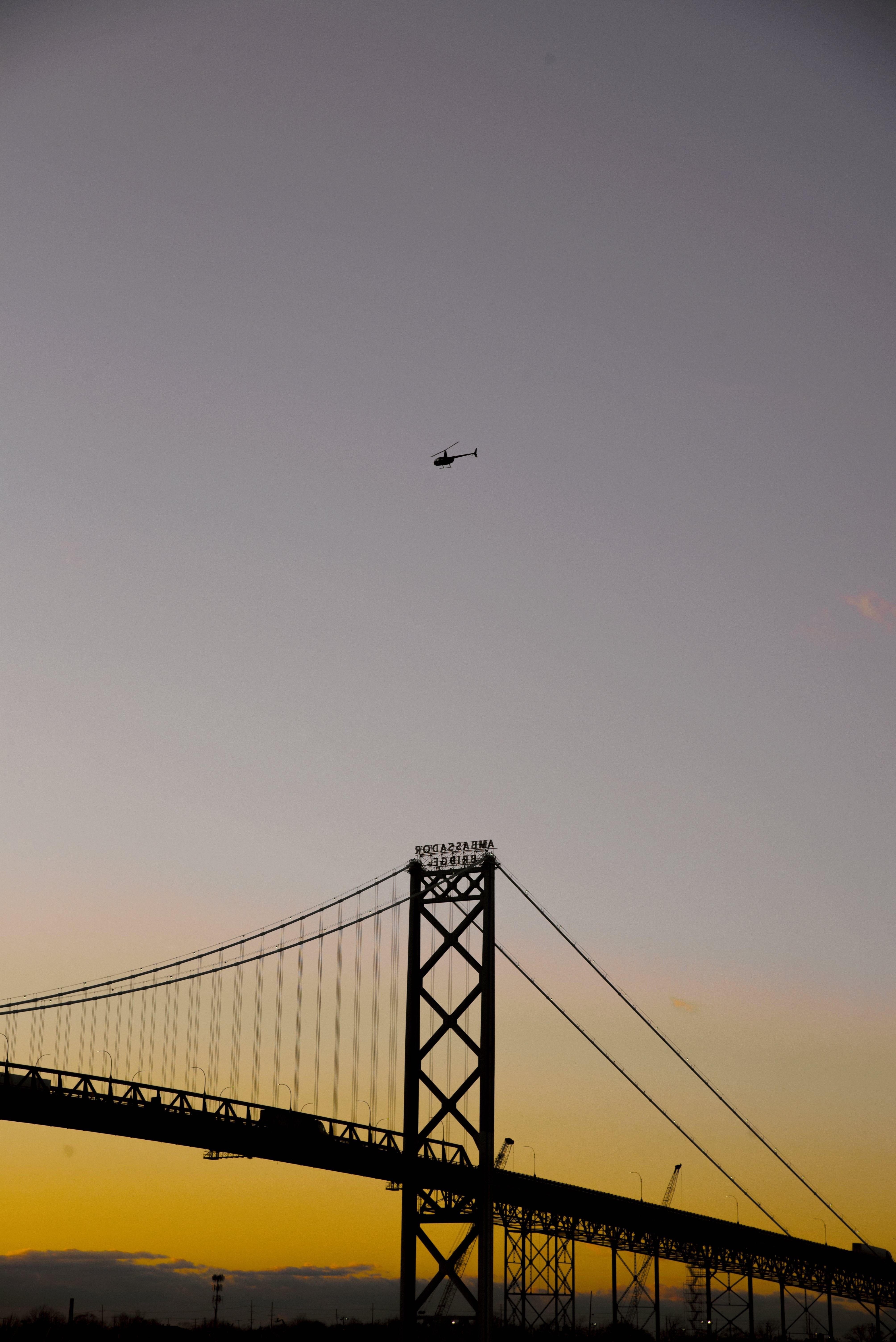 Sunset Silhouette: Grand Bridge and Helicopter Over the Horizon