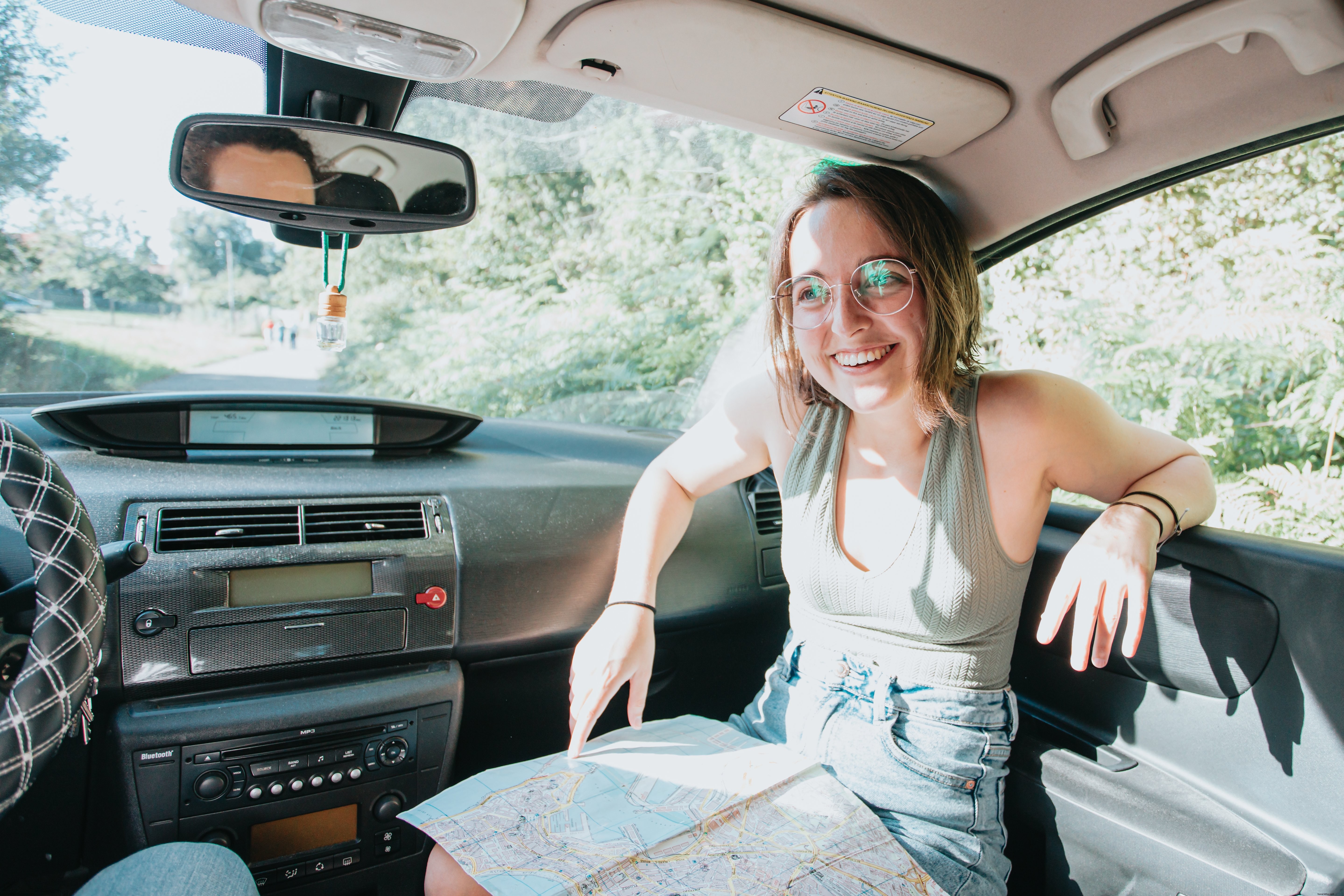 Candid Road‑Trip Moment: Woman Smiles Holding a Map Inside Her Car
