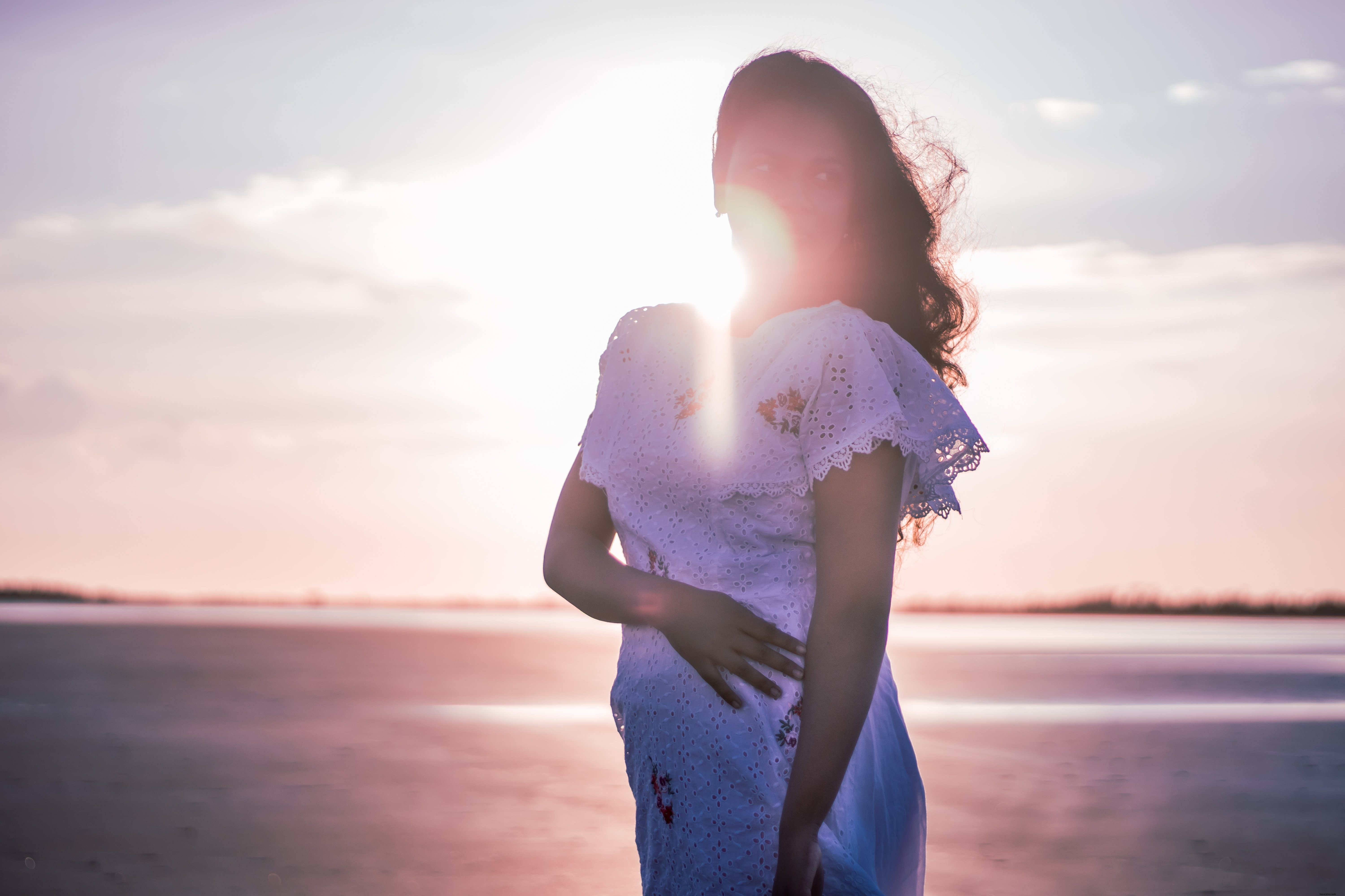 Sunset Serenity: A Woman in White Graces the Beach at Dusk