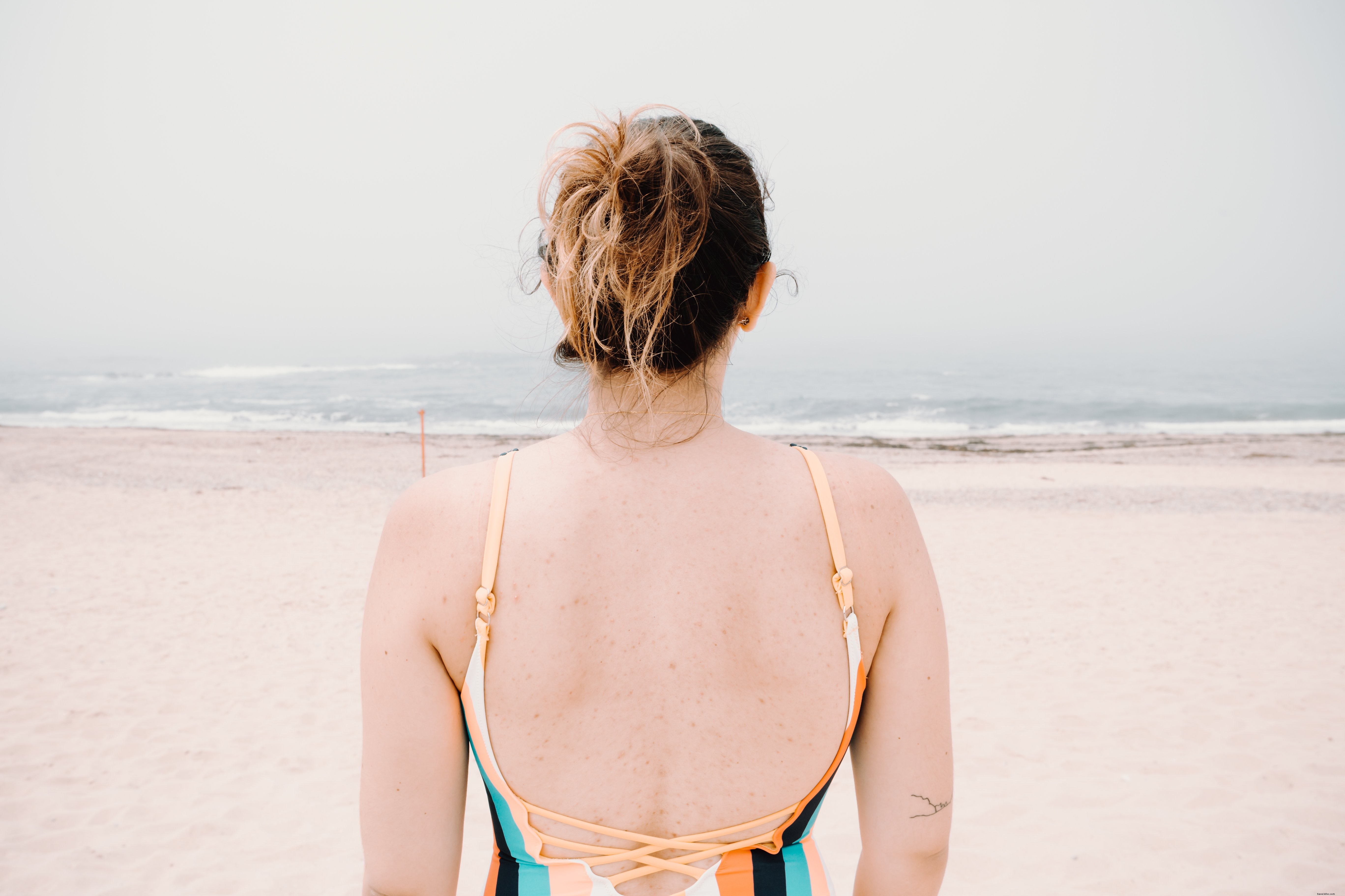 Stunning Coastal Scene: Person Facing Gentle Waves on a Sunny Beach